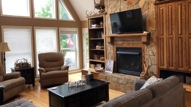 A spacious living room with a stone fireplace, a large flat-screen TV, and comfortable seating.