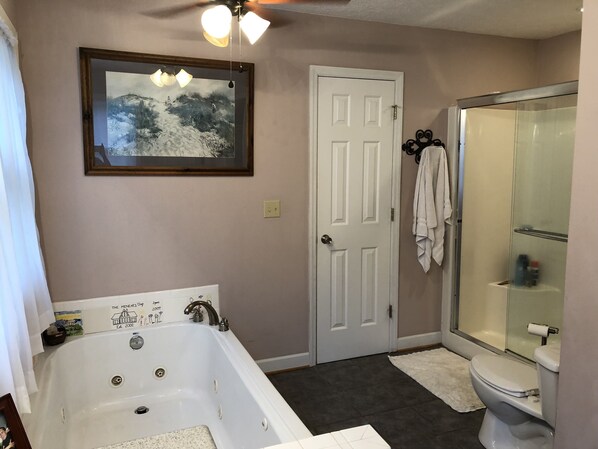 A bathroom with a bathtub, toilet, and glass shower enclosure. - The Gathering House (Stuart)