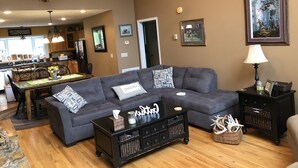 A living room with a sectional sofa, a coffee table, a fireplace, and a mounted deer head.