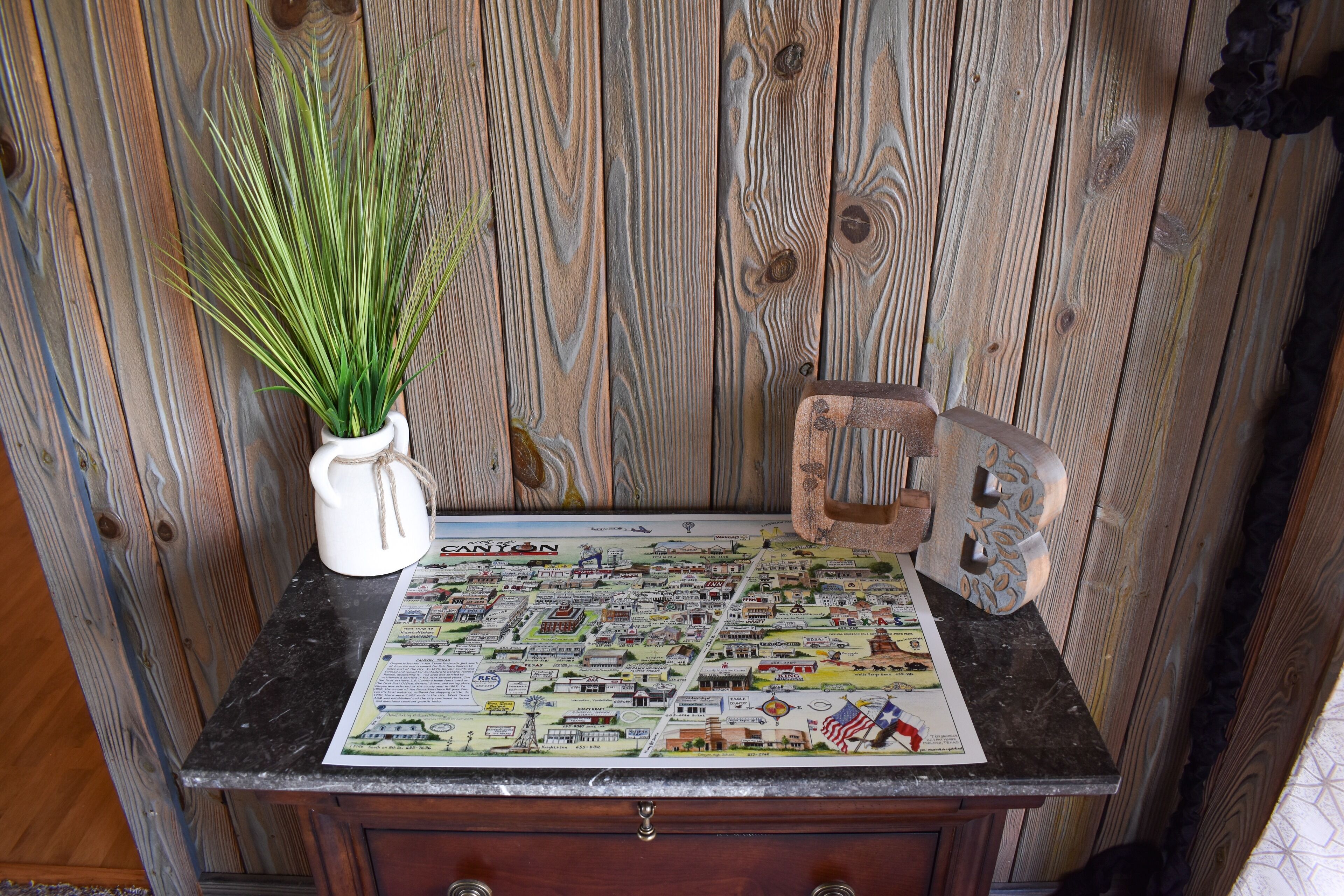A map of a town on a wooden table with a plant and a decorative item.