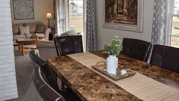 A dining area with a marble table, leather chairs, a white vase with flowers, and a painting above the table. - The Cozy Buffalo near Palo Duro Canyon & WTAMU (Canyon)