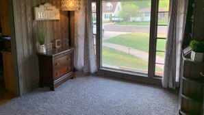A room with a wooden ceiling, a large window with curtains, a wooden dresser with a sign reading "Farm House," and a small plant on the dresser. - The Cozy Buffalo near Palo Duro Canyon & WTAMU (Canyon)