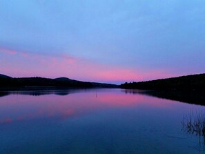 A calm lake at dusk with a clear reflection of the sky.