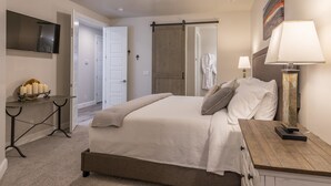 A bedroom with a bed, bedside table, lamp, and a TV mounted on the wall. - 2 Much Fun (St. George)