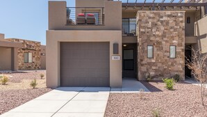 A modern building with a garage door, a balcony with red cushions, and a stone facade. - 2 Much Fun (St. George)