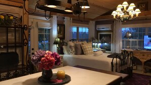 A cozy room with a bed, a table with a vase of flowers, and a desk with a computer. - Intercostal Waterfront Private Cottage Retreat Close to Mayo Clinic (Jacksonville)