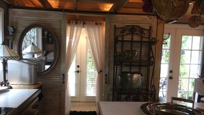 A kitchen with wooden cabinets, a sink, a stove, and a dining area with a table and chairs. - Intercostal Waterfront Private Cottage Retreat Close to Mayo Clinic (Jacksonville)