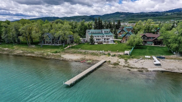 A lakeside property with a dock, multiple houses, and a mountainous backdrop. - Spinnaker Point #2 - BEACH FRONT! Come Stay At Our Lake House in Bear Lake, Utah! (Garden City)