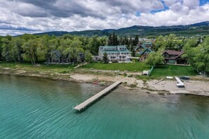 A lakeside property with a dock, multiple houses, and a mountainous backdrop. - Spinnaker Point #2 - BEACH FRONT! Come Stay At Our Lake House in Bear Lake, Utah! (Garden City)