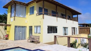 Un edificio de dos pisos con balcón, piscina y zona de patio.