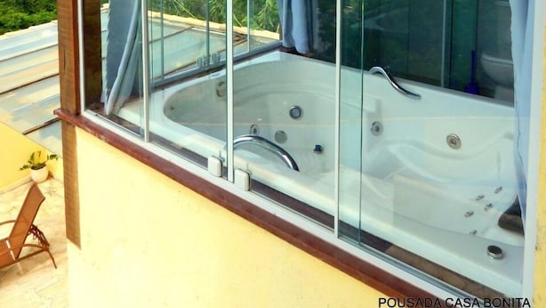 Un jacuzzi con paredes de vidrio y vistas a un paisaje verde.