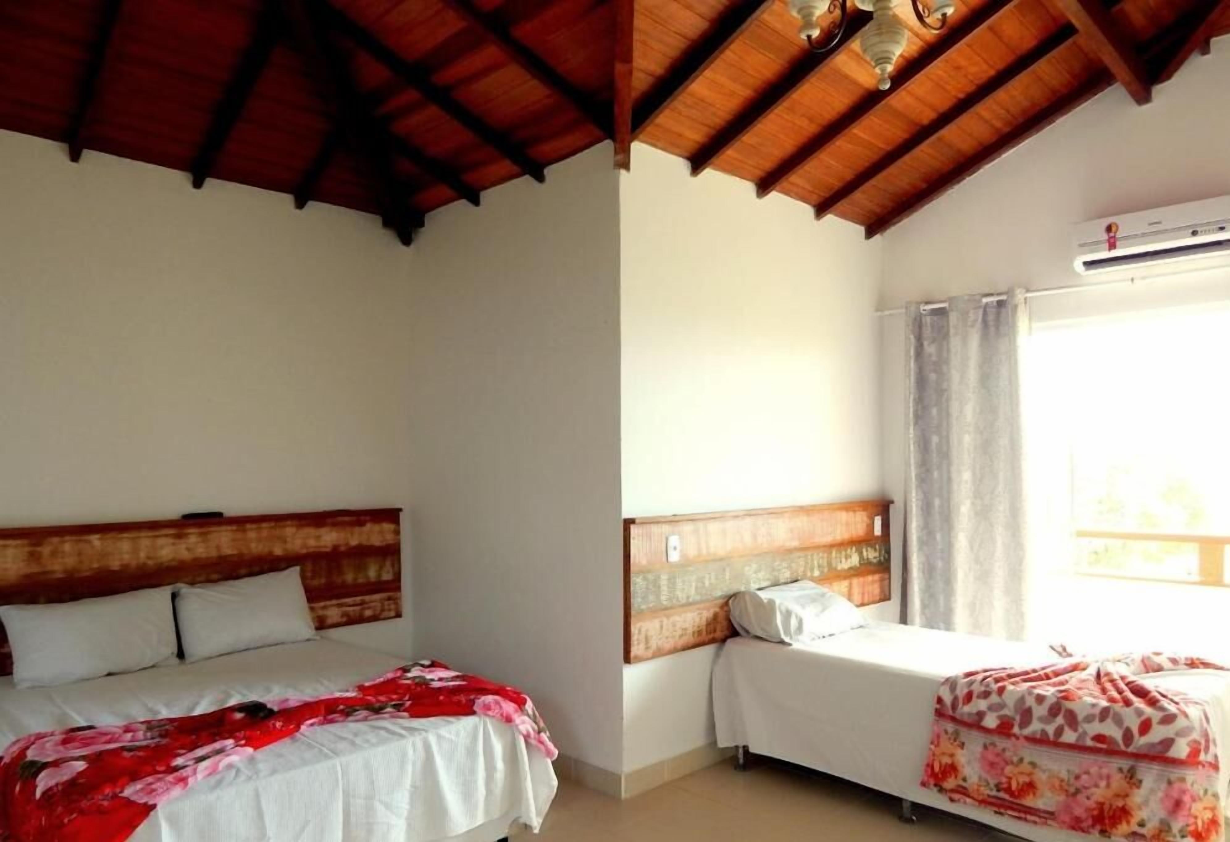Una habitación con dos camas, cabeceros de madera, un ventilador de techo y un equipo de aire acondicionado.