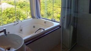 Un baño con un ventanal grande, una bañera y una ducha con mampara de vidrio.