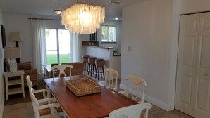 A dining area with a wooden table, white chairs, and a hanging light fixture.