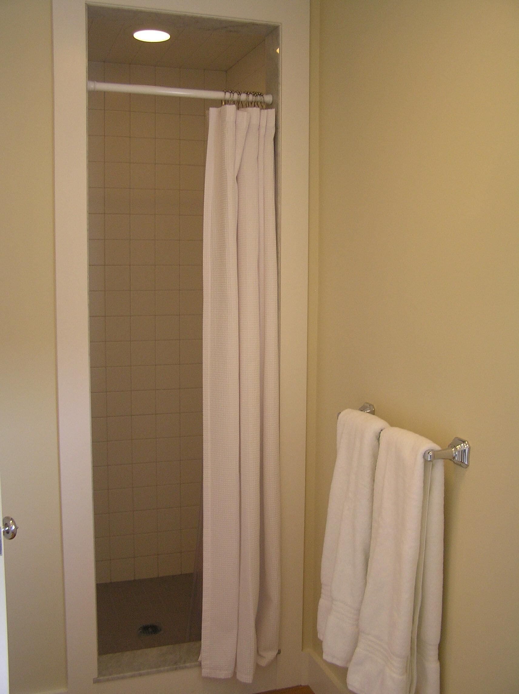 Une salle de bain avec une douche, un porte-serviettes et une porte.