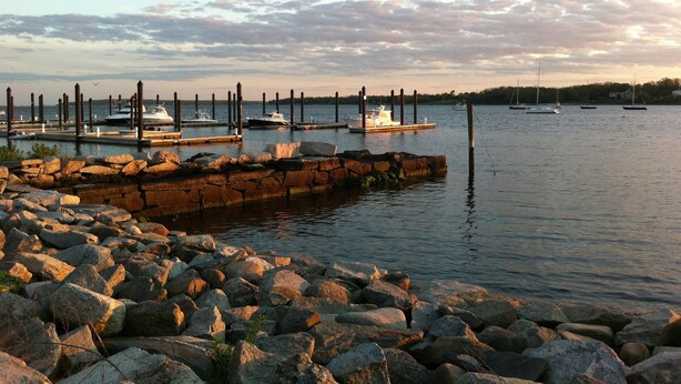 A marina with boats docked at wooden piers, surrounded by a rocky shoreline.