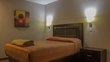 A hotel room with a bed, bedside tables, and wall-mounted lights.