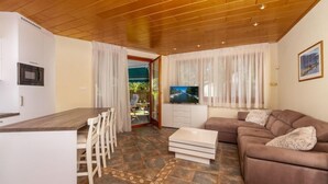 Un soggiorno moderno con soffitto in legno, un divano, una televisione e un'area pranzo con sedie e un tavolo.