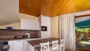 Una cucina moderna con mobili bianchi, un'isola in legno e un'area pranzo con sedie bianche.