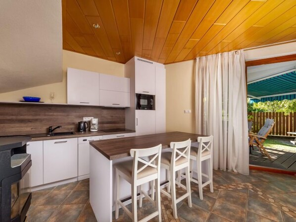 A modern kitchen with white cabinets, a wooden island, and a dining area with white chairs.