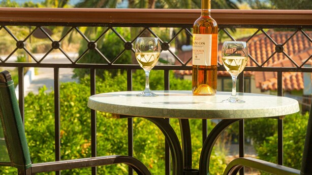 A table with a bottle and two glasses on a balcony overlooking the sea. - Stella Bay (Samos)