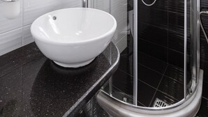 A modern bathroom with a white sink, a glass-enclosed shower, and a large mirror. - Stella Bay (Samos)
