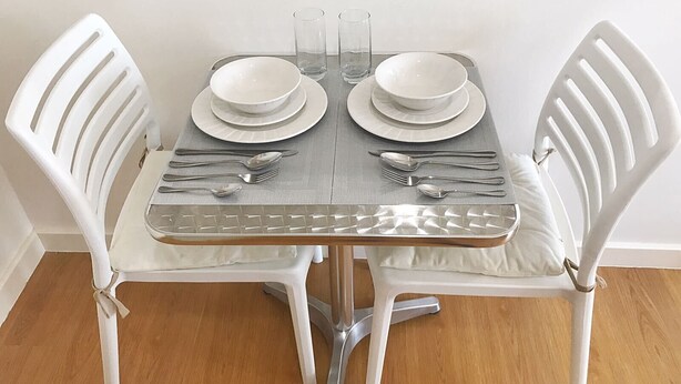 A dining table set with white chairs, plates, cutlery, and glasses. - 8Adriatico2 Contemporary Luxurious Studio (Manila)