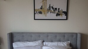 A neatly made bed with a grey upholstered headboard and white bedding. - 8Adriatico2 Contemporary Luxurious Studio (Manila)