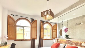 A hotel room with a large bed, wooden arched windows, a desk, and a modern chandelier. - Unique House 5Br- Private SPA&POOL - StayInSeville (Sevilla)