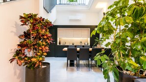 A modern dining area with a high ceiling, a black and white color scheme, and large potted plants. - Unique House 5Br- Private SPA&POOL - StayInSeville (Sevilla)