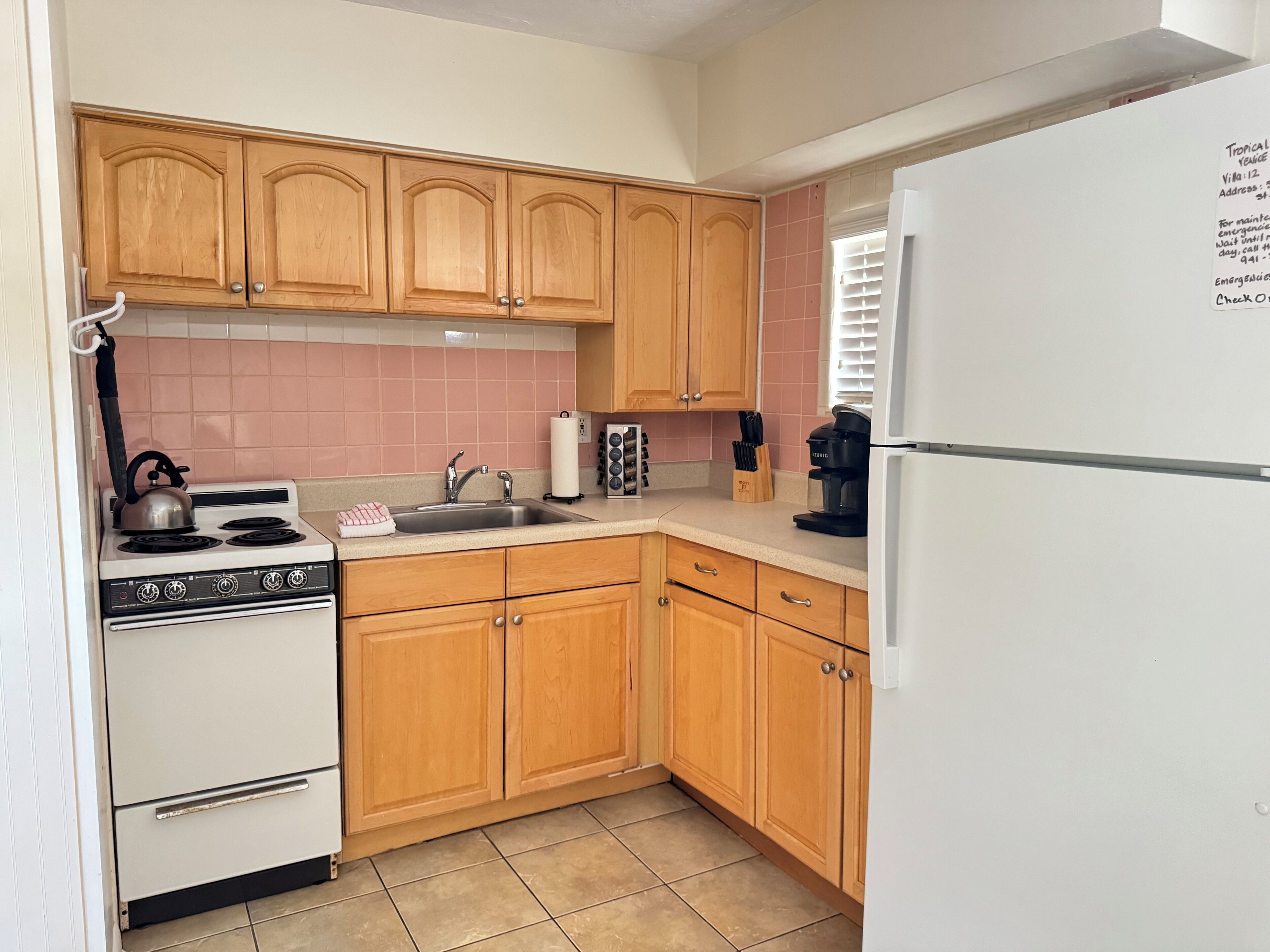 A kitchen with wooden cabinets, a stove, a sink, and a refrigerator.
