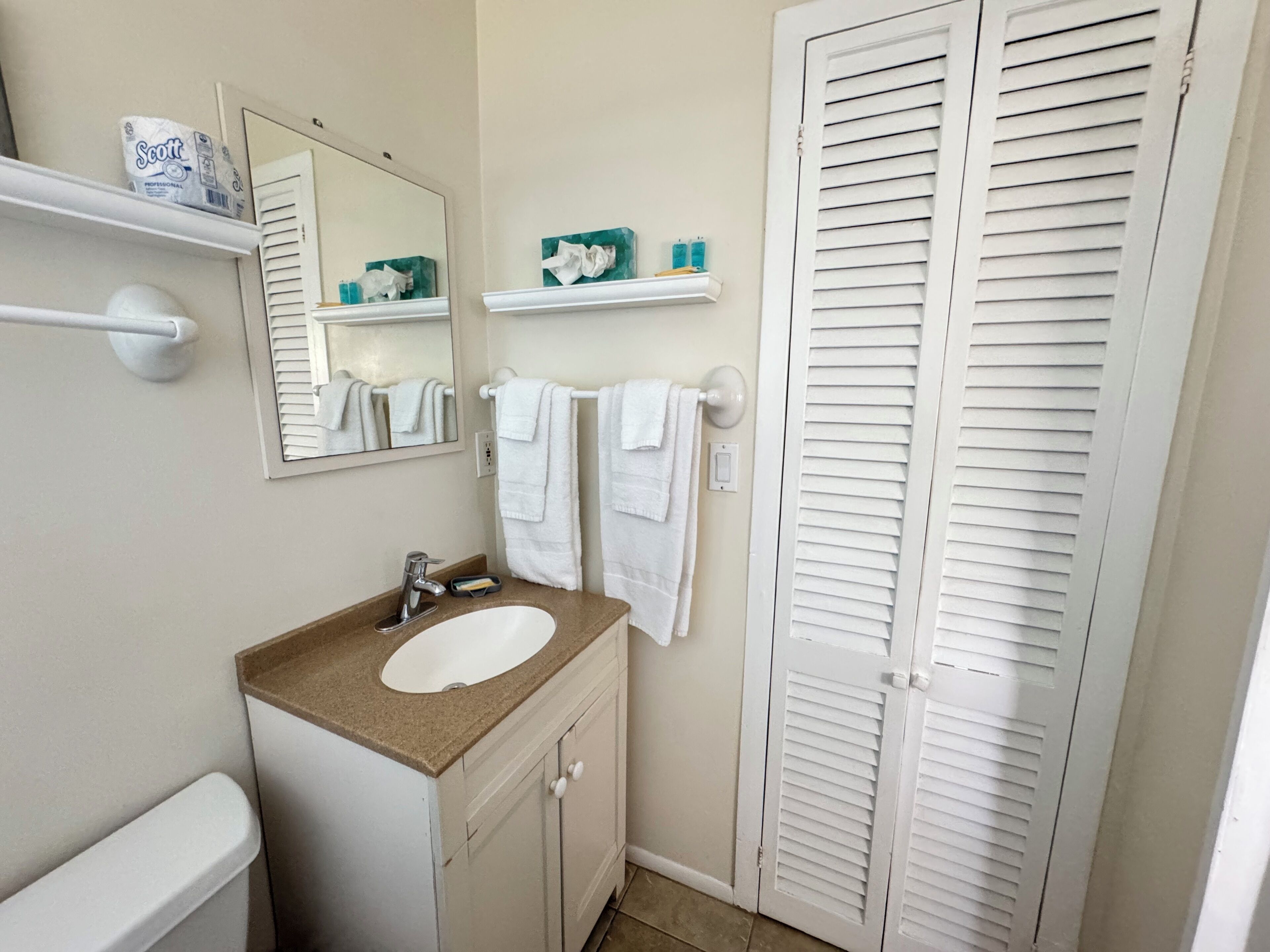 A bathroom with a sink, mirror, towel rack, and a toilet.
