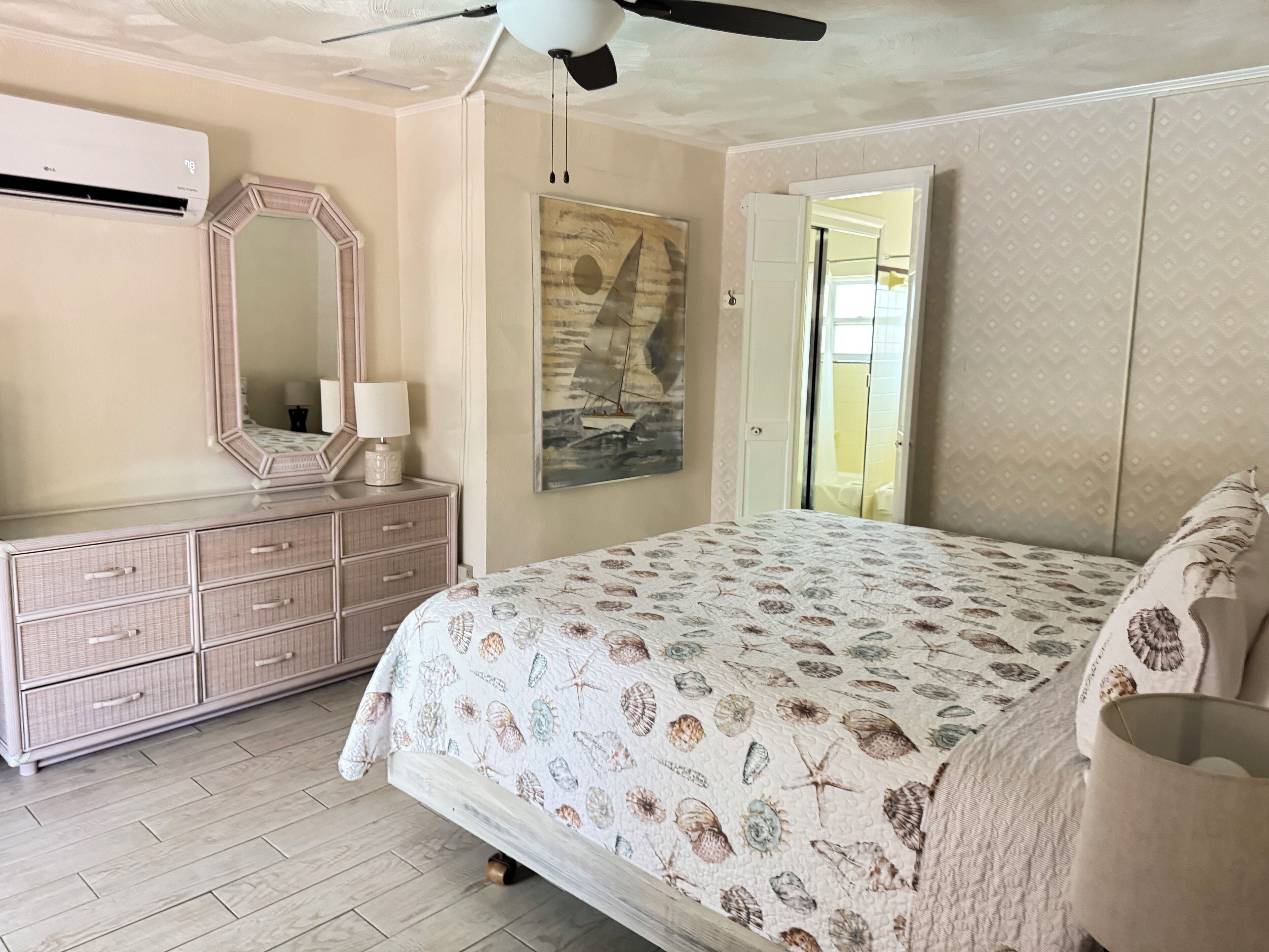 A bedroom with a bed, dresser, mirror, and a painting on the wall.