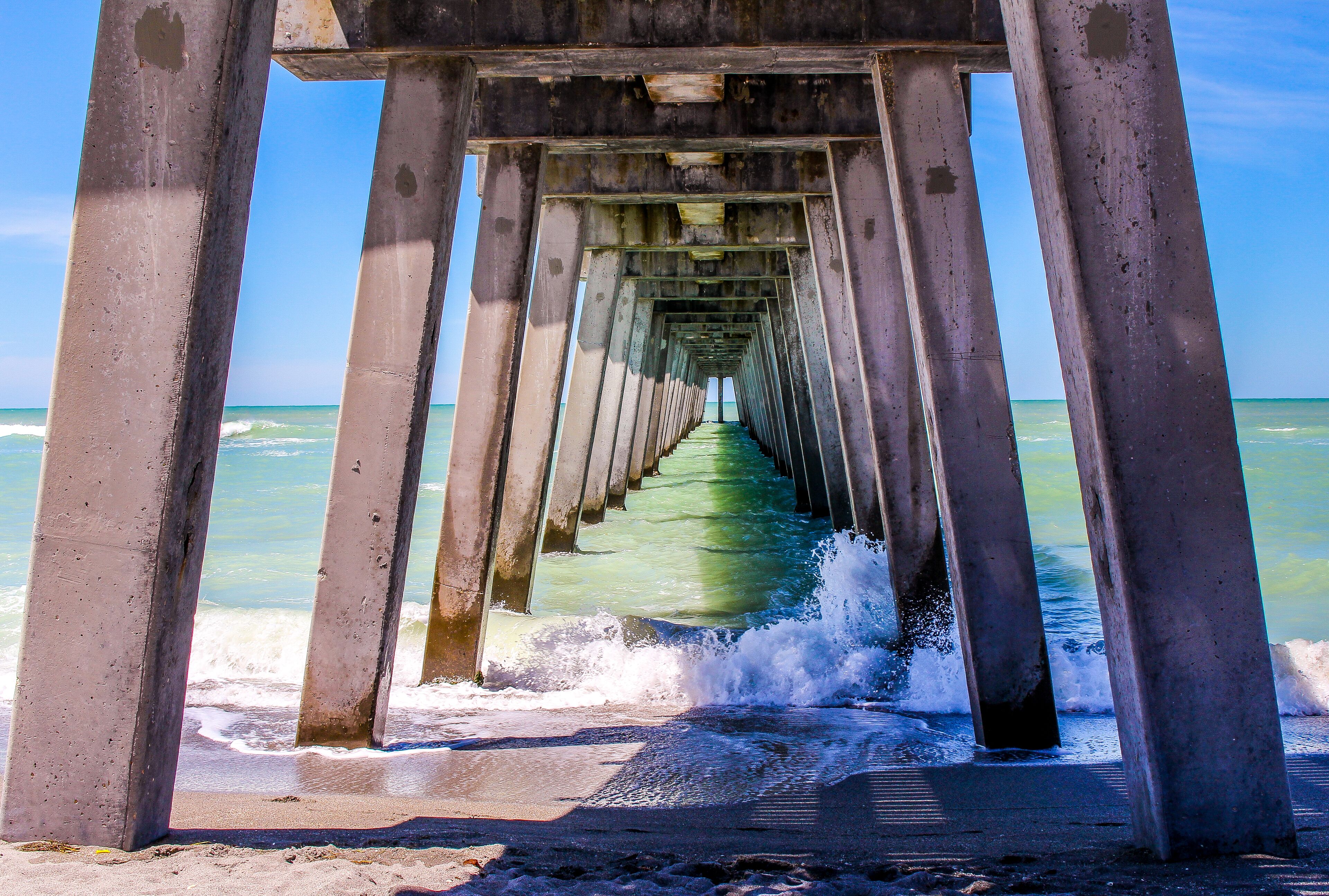 A pier structure with concrete pillars and a walkway leading into the ocean.