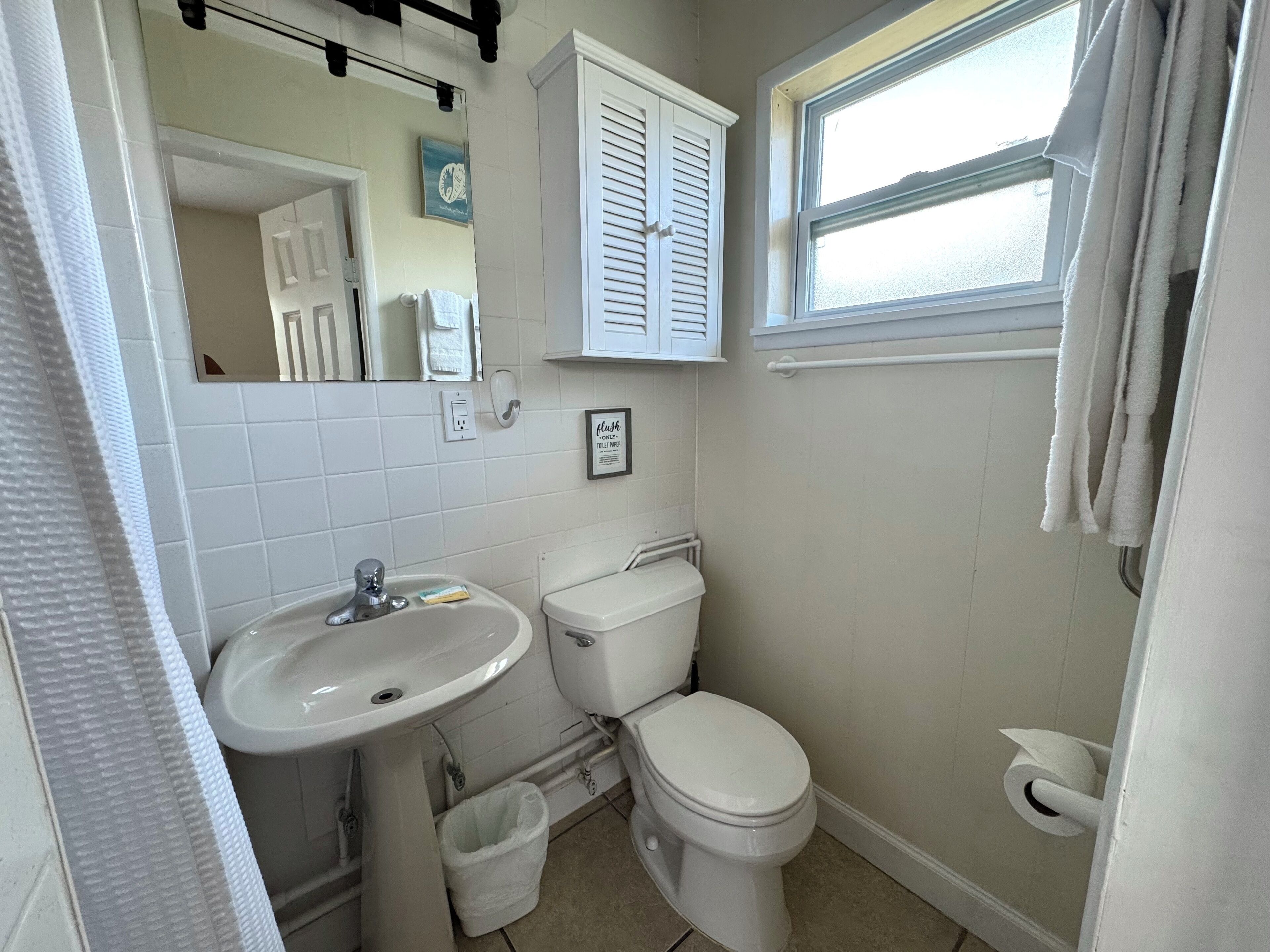 A bathroom with a sink, toilet, and window.