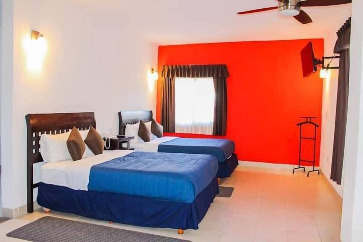 A hotel room with two beds, a desk, and a chair.