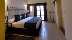 A hotel room with a bed, a ceiling fan, a TV mounted on the wall, and a window with curtains. - Real de la Presa (Guanajuato)