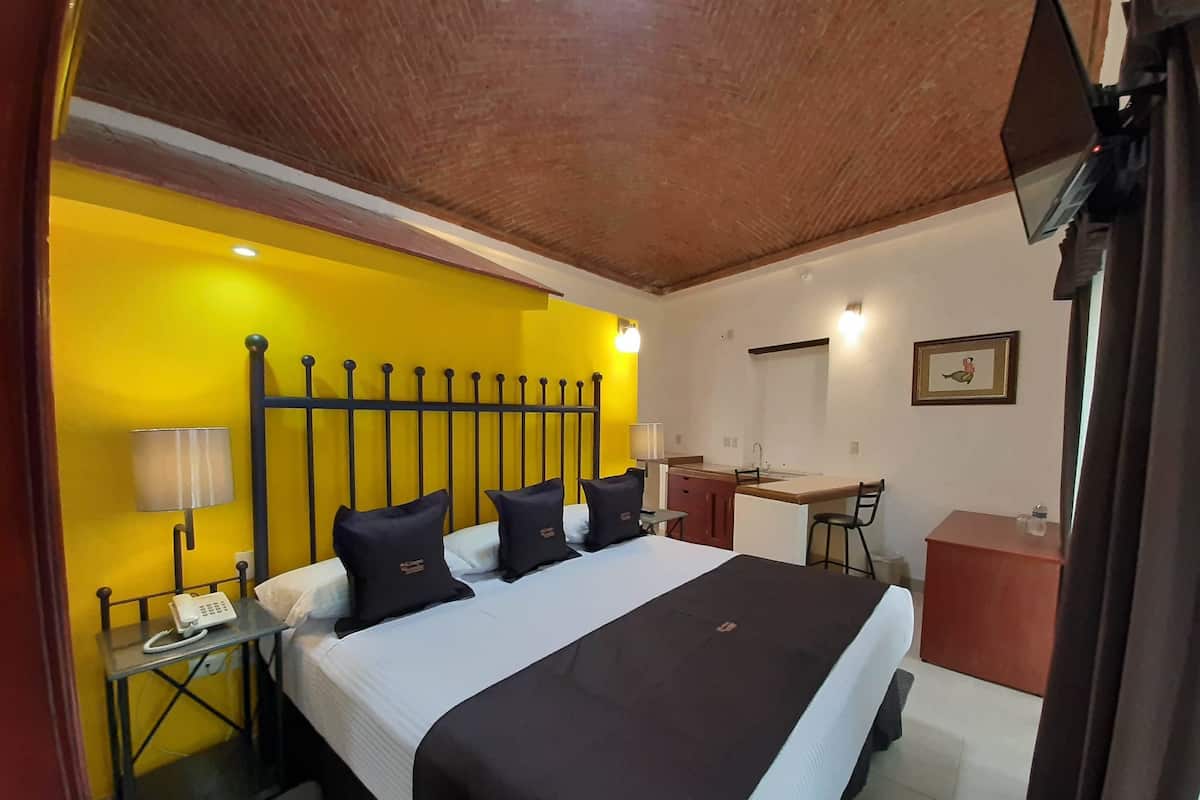 A hotel room with a bed, bedside table with a lamp, a desk, and a chair.