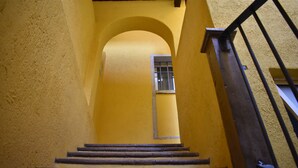 A staircase with wooden steps leading up to a landing, surrounded by yellow walls and a metal railing. - Real de la Presa (Guanajuato)