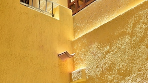 A multi-level interior with a yellow wall, a wooden window, and a metal railing. - Real de la Presa (Guanajuato)