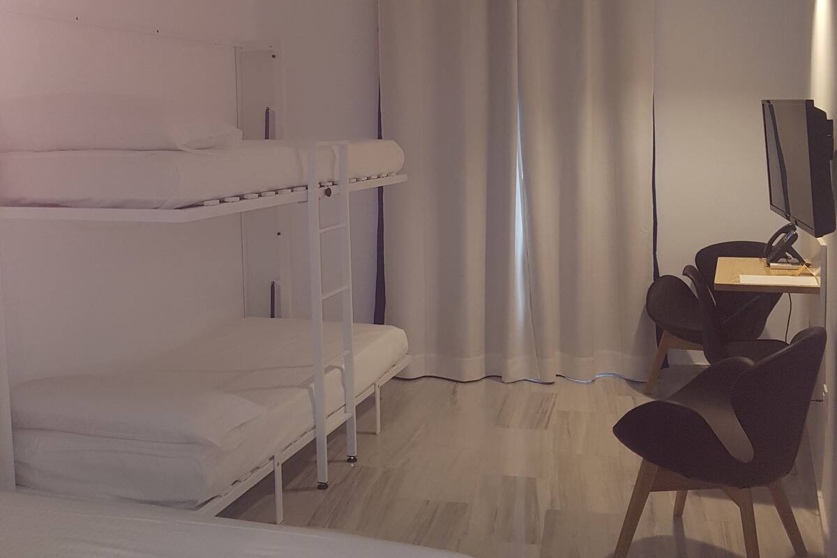 A bedroom with bunk beds, a desk with a computer, and a chair.