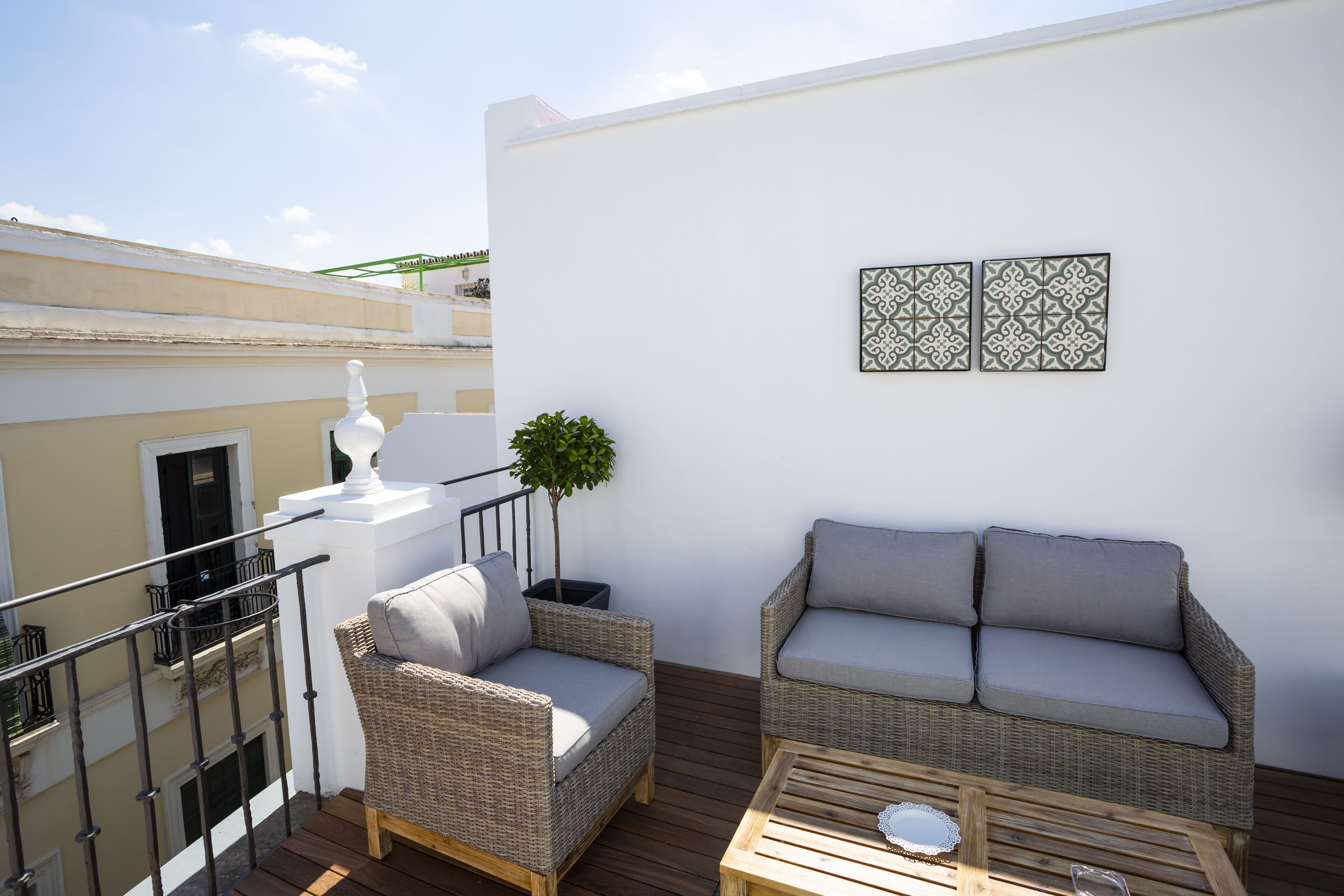 A balcony with wicker furniture, a small table, and decorative wall art.