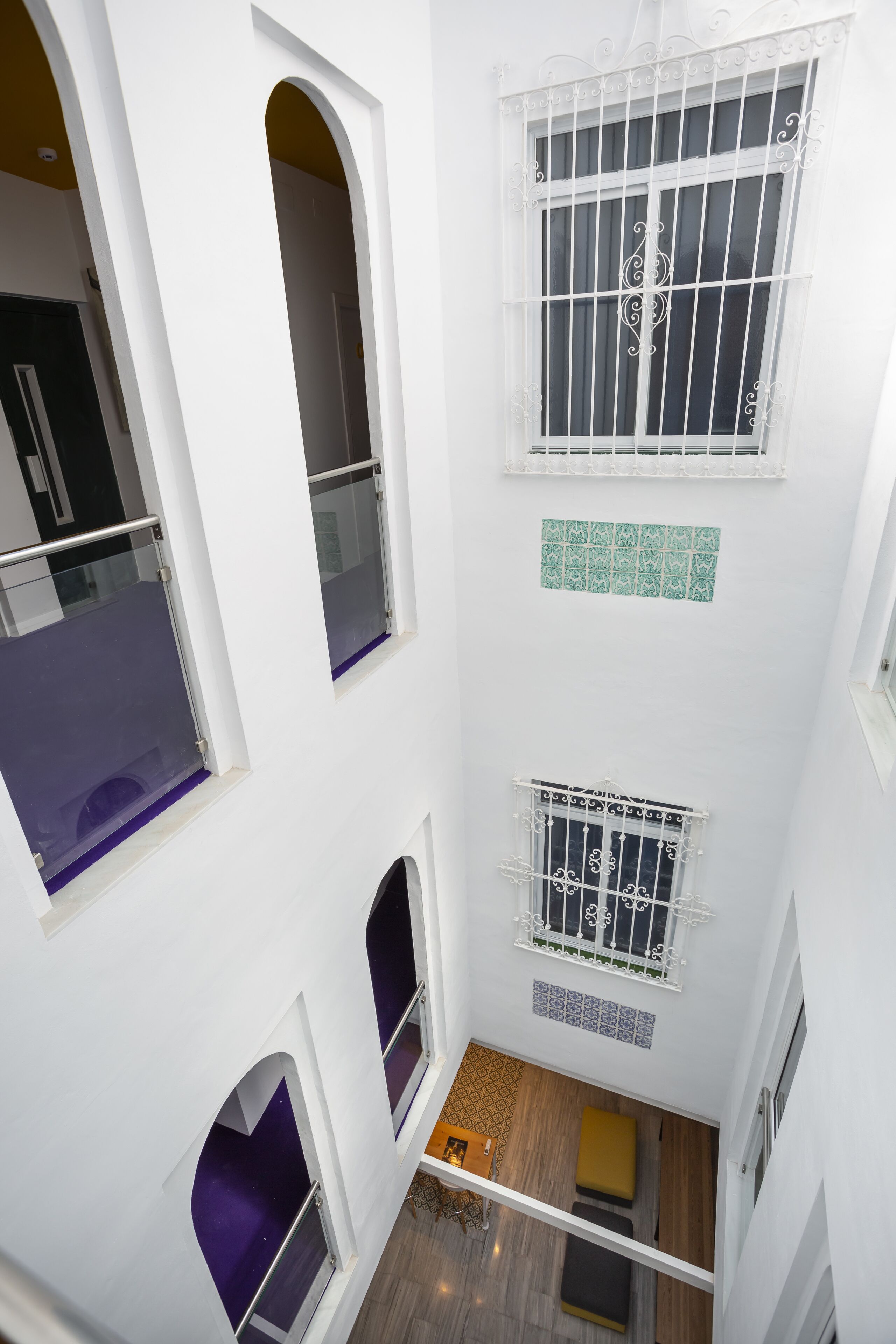 A multi-level interior with white walls, a wooden floor, and a small seating area with cushions.