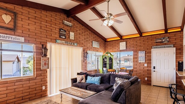 A cozy living room with a brick wall, a ceiling fan, and a couch with pillows. - Upgraded lake view (Lake Havasu City)