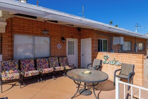 A patio area with a brick wall, a round table, and colorful chairs. - Upgraded lake view (Lake Havasu City)