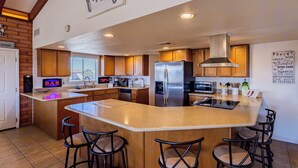 A spacious kitchen with a large island, wooden cabinets, stainless steel appliances, and a bar area with stools. - Upgraded lake view (Lake Havasu City)