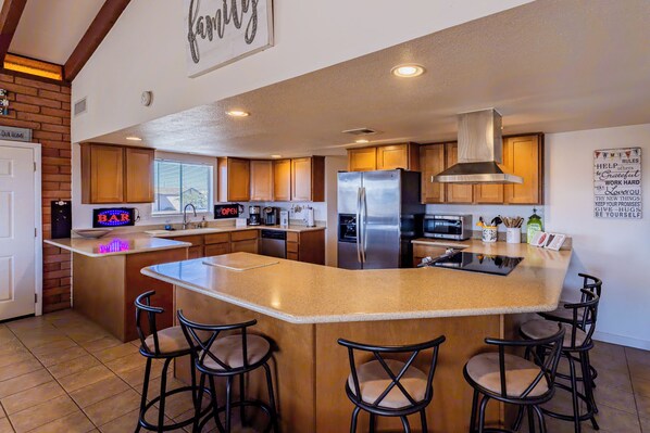 A spacious kitchen with a large island, wooden cabinets, stainless steel appliances, and a bar area with stools. - Upgraded lake view (Lake Havasu City)