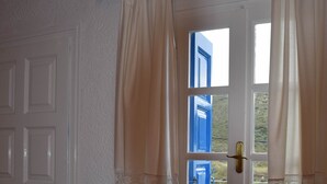 A room with a dining table, chairs, a window with blue shutters, and a door. - House Near Sea - Andros (Andros)