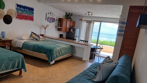A room with two beds, a desk, and a view of the ocean.