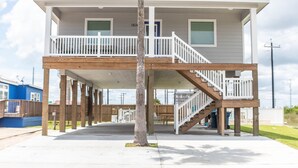 A two-story house with a covered porch and a wooden staircase. - JoJo's Heaven - in town Port Aransas, private pool. 4 BR/3bath. Perfect getaway! (Port Aransas)